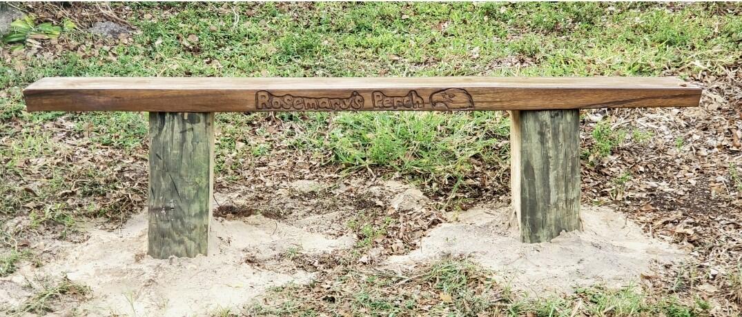 A wooden bench with the words "Rosemary's Perch" carved into the side.